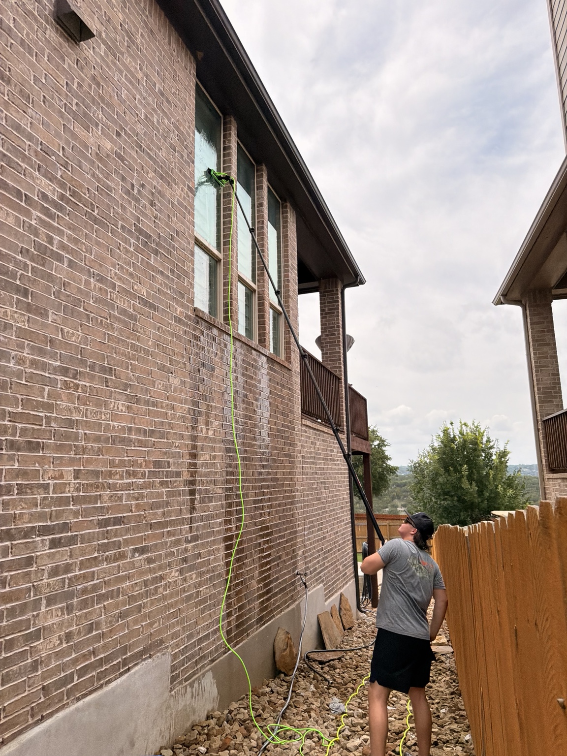 Precise Panes technician using a pure-water pole on a multi-story brick home in Austin, TX